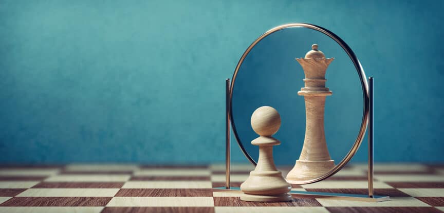 Ein Schachbauer sieht sich im Spiegel als Schachkönigin