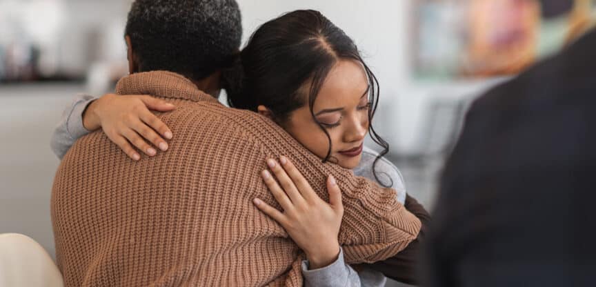 Frau umarmt eine Person in einem emotionalen Moment.