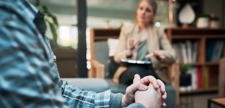 Mann in Therapiegespräch mit einer Therapeutin in gemütlicher Praxis