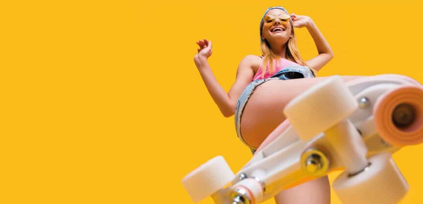 Junges Mädchen von unten aufgenommen in kurzen Shorts auf Rollschuhen.