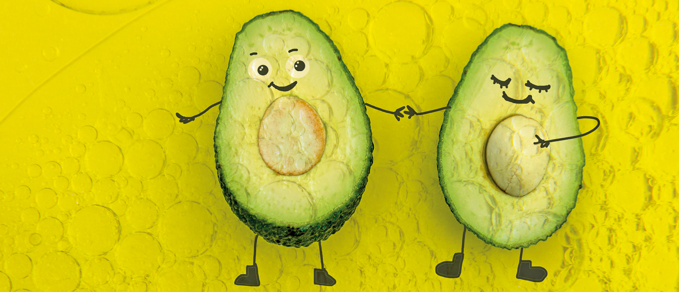 Zwei Avocado-Hälften auf gelbem Grund mit lustigen aufgemalten Gesichtern halten Händchen.