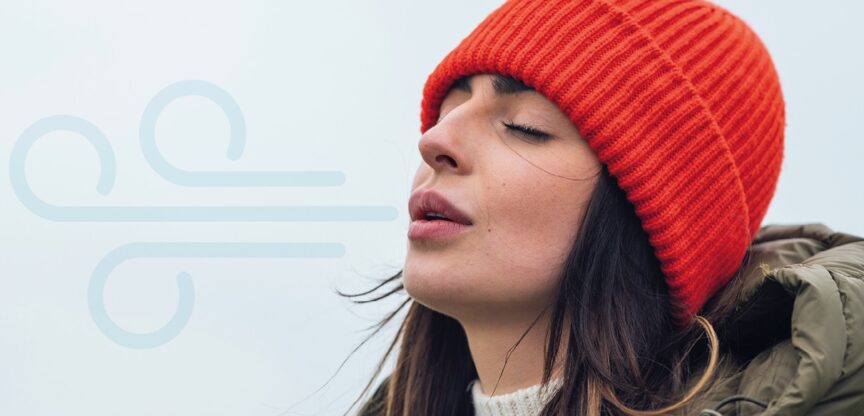 Junge Frau mit roter Mütze atmet mit geöffnetem Mund und geschlossenen Augen ein.