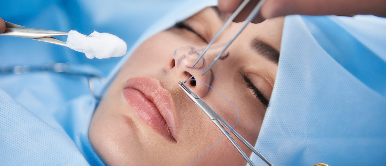 Chirurgische Instrumente an der Nase einer jungen Frau, die mit geschlossenen Augen am OP-Tisch liegt.