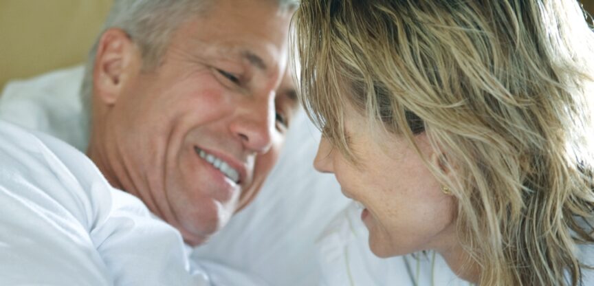 Älteres Paar im Bett, nur Köpfe sichtbar.