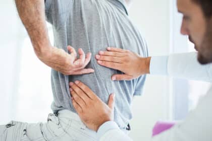Arzt untersucht den Rücken eines Patienten, der auf Schmerzen im unteren Rückenbereich hinweist.