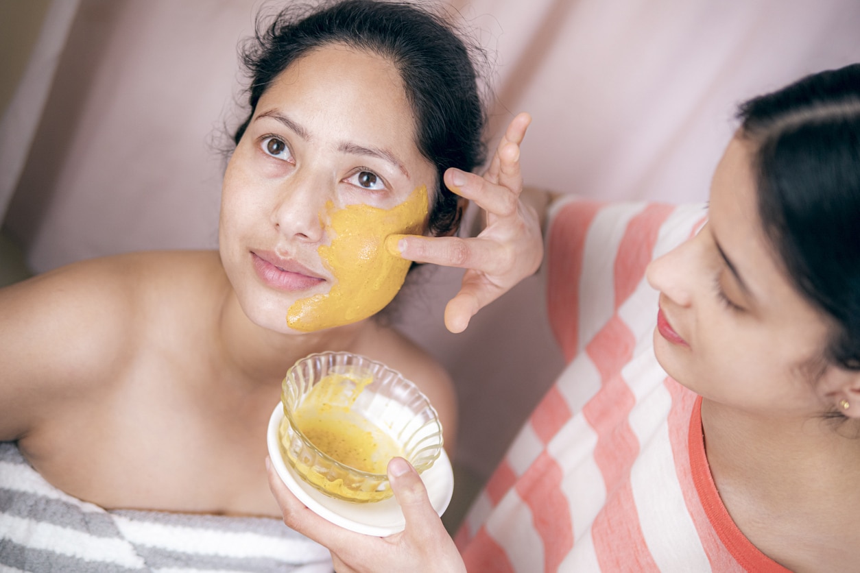 Frau bekommt gelbe, natürliche Gesichtsmaske aufgetragen
