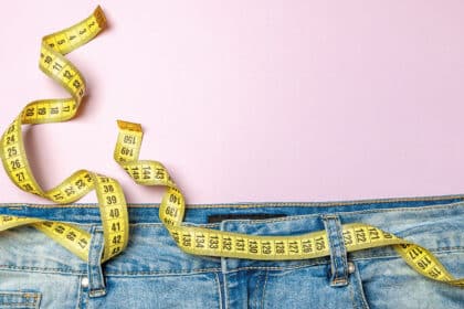 Jeans mit Maßband um den Bund als Symbol für Gewichtsverlust, Abnehmen und Körpermaße.