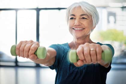 Ältere Frau trainiert mit Kurzhanteln und lächelt – Symbolbild für Krafttraining, Muskelaufbau und Fitness im Alter.