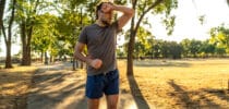 Erschöpfter Jogger wischt sich bei sommerlicher Hitze den Schweiß von der Stirn – Symbolbild für körperliche Belastung und Sport bei hohen Temperaturen.